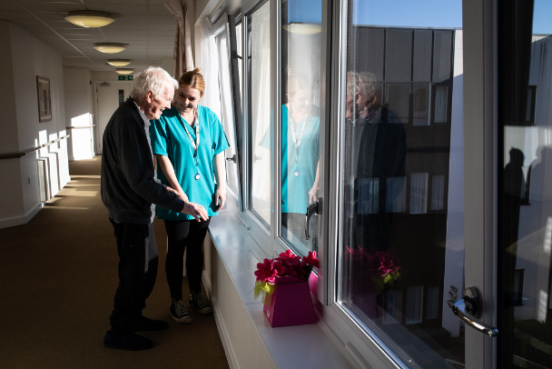 resident looking out of a window with care giver